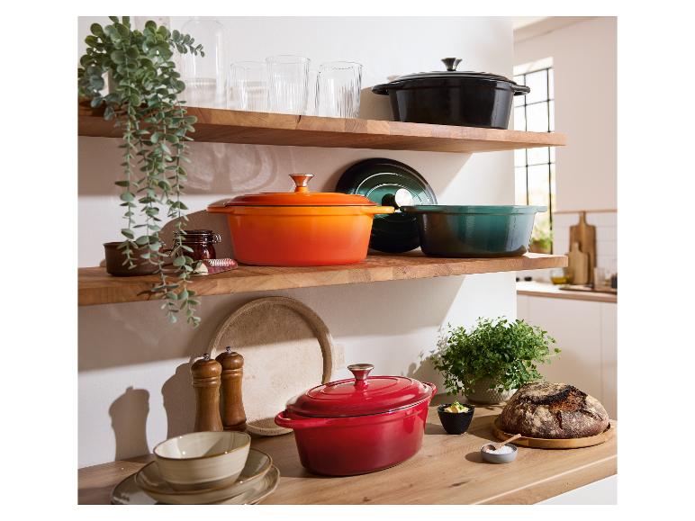 Casseroles Le Creuset en fonte de différentes couleurs sur des étagères en bois dans une cuisine élégante.