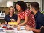 Une femme sert un gâteau d'anniversaire avec des bougies à ses amis.