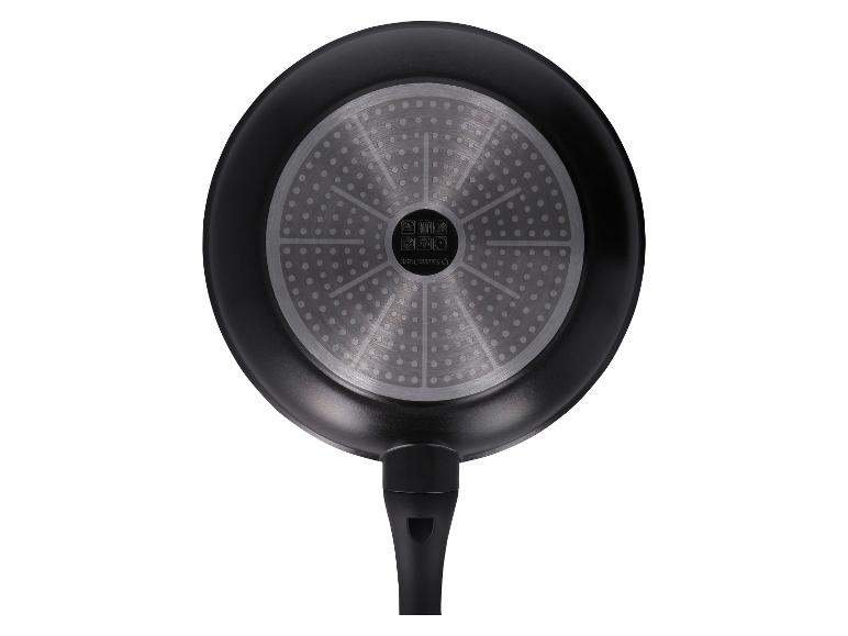 Vue de dessous d'une poêle à frire noire avec une base à induction argentée et une poignée noire.