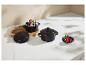 Casseroles en céramique noires avec fruits et chocolat sur une surface en marbre clair.