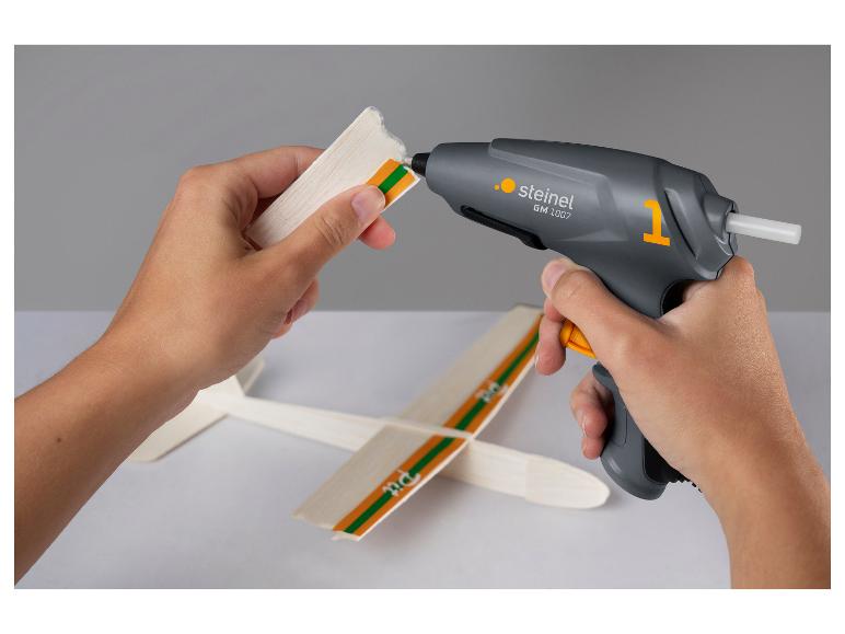Mains collant un modèle d'avion avec le pistolet à colle chaude STEINEL GlueMatic 1007.
