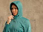 Une femme porte une veste softshell verte à capuche.