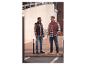 Deux hommes en chemises à carreaux, doudounes sans manches, jeans et chaussures décontractées en ville.