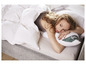 Une femme est couchée dans un lit avec un oreiller et une couette Fjällräven.