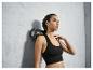 Une femme avec un soutien-gorge de sport noir et un rouleau en mousse.