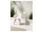 Chaise design blanche, lampadaire blanc et plantes vertes pour un espace extérieur élégant.