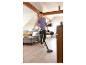 Homme nettoyant un parquet clair avec un aspirateur sans fil dans un salon moderne.