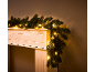 Guirlande de Noël lumineuse sur un manteau de cheminée blanc.