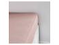 Un drap housse rose sur un lit.