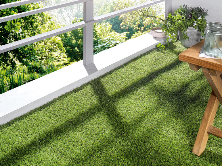Gazon artificiel sur un balcon avec une table en bois et des plantes.