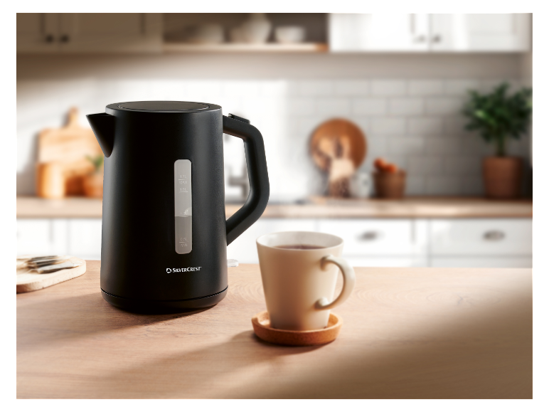 Une bouilloire noire SilverCrest sur une table en bois à côté d'une tasse de thé.