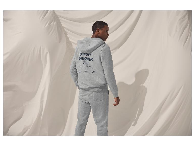 Homme en sweat à capuche gris et pantalon de survêtement avec logo 'Sunday Couching Club'.