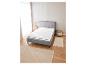 Un lit gris avec un matelas et un tapis dans une chambre