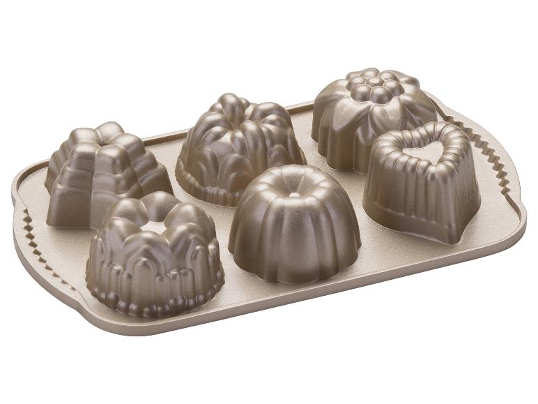 Un moule à pâtisserie doré avec six moules à mini-bundt de formes différentes.
