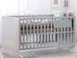 Un lit bébé gris avec une couette rose et grise.
