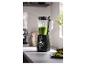 Mixeur avec smoothie vert sur un comptoir de cuisine, à côté de citrons verts coupés et de noix.