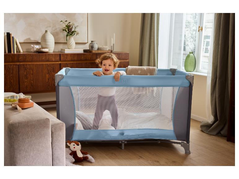 Bébé dans un lit de voyage bleu dans le salon.