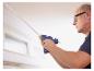Homme utilise un pistolet à colle sans fil LIVARNO® CG270 pour fixer une bande au plafond.
