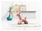 Une statuette de chien en ballon rose sur un dessous-de-plat rond en jute.