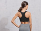 Une femme porte un soutien-gorge de sport noir et un legging gris.