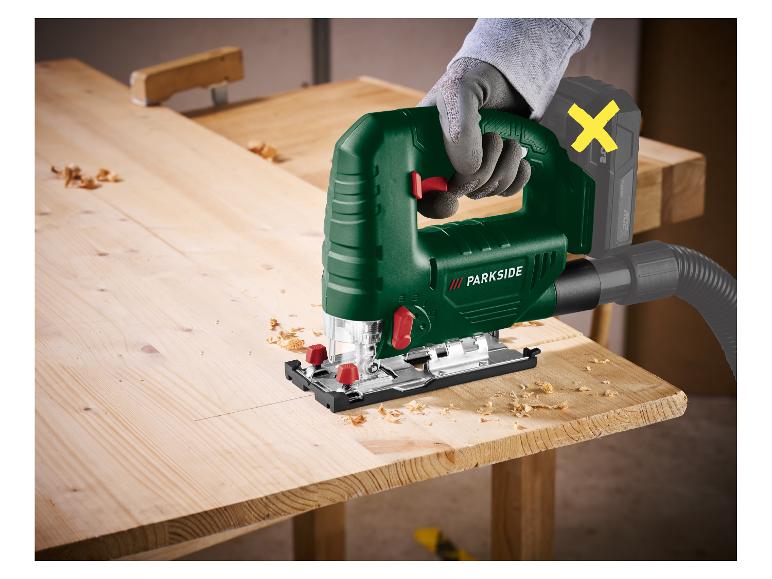 Scie sauteuse sans fil avec aspirateur sur bois, tenue par une personne gantée.