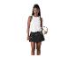 Femme en débardeur blanc et jupe noire, tenant une raquette de badminton.