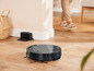 Un aspirateur robot noir sur un sol en bois.