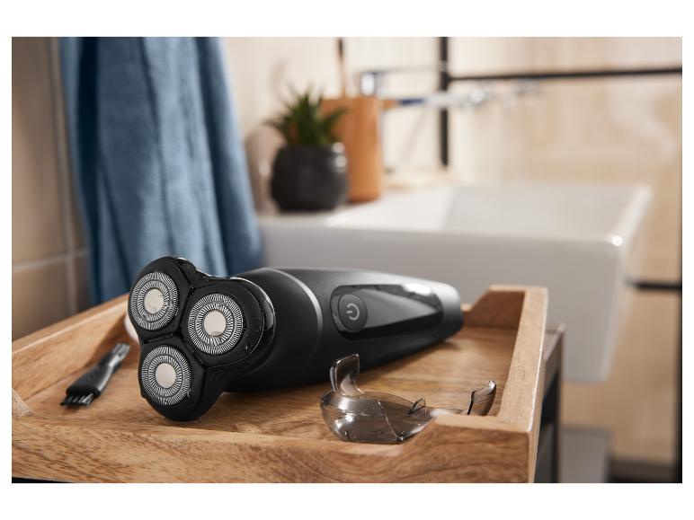 Rasoir électrique noir sur un plateau en bois dans une salle de bain.
