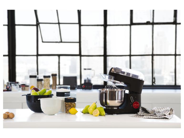 Robot pâtissier et ustensiles de cuisine sur un comptoir blanc devant une fenêtre.