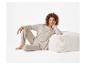 Femme en ensemble loungewear beige, appuyée sur un pouf côtelé.