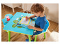Un enfant dessine sur un tableau magnétique assis à une table et une chaise Peppa Pig.