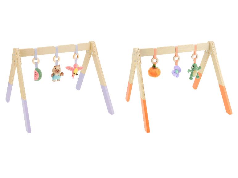Deux portiques d'éveil en bois avec des jouets en peluche suspendus, l'un avec des accents violets, l'autre orange.