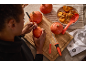 Personne sculptant des citrouilles d'Halloween avec des outils de sculpture et des graines.