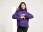 Une femme porte un pull en tricot violet à col roulé.