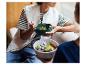 Deux personnes mangeant des salades dans des bols, l'une avec une fourchette.