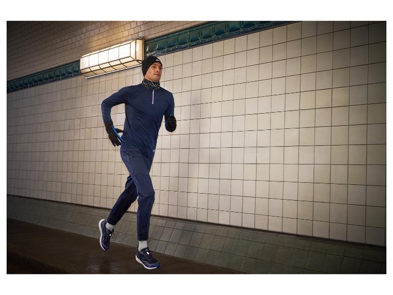 Homme courant dans un tunnel, portant un sweat à capuche, un pantalon et des chaussures de course.