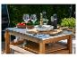 Table d'extérieur en bois avec plan de travail en métal, verres à vin et vaisselle.