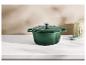 Cocotte en fonte verte sur un comptoir blanc avec un pot décoratif et un petit bol.