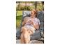 Une femme se relaxe dans un fauteuil suspendu gris confortable en extérieur.