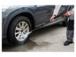 Une personne nettoie une roue de voiture avec un nettoyeur haute pression.