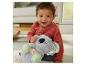 Bébé joyeux tenant une peluche koala au ventre lumineux, assis sur un tapis.