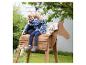 Deux enfants souriants assis sur un cheval jouet en bois à l'extérieur.