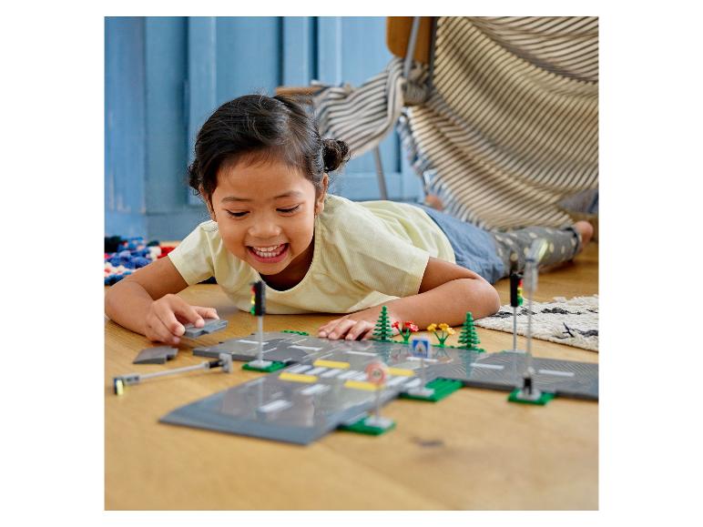 Une enfant joue avec des LEGO® City : routes, feux et végétation.