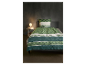 Parure de lit verte et blanche à motifs sur un lit.