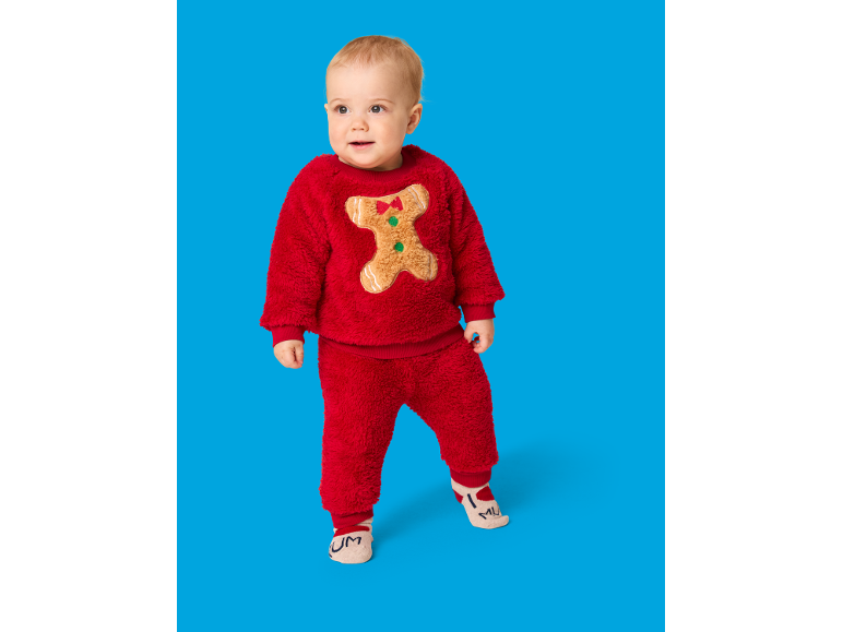 Bébé en ensemble de Noël rouge et duveteux avec un bonhomme de pain d'épices
