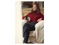 Femme en pull rouge et pantalon noir, assise dans un fauteuil avec une tasse.
