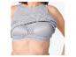 Femme portant un débardeur gris côtelé remonté pour révéler un soutien-gorge de sport gris.