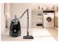 Aspirateur traîneau noir avec tuyau et tube, dans une buanderie avec machine à laver.