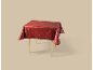 Nappe de Noël rouge avec motifs festifs dorés sur une table en bois.