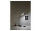 Une lampe de bureau noire sur un bureau avec un carnet et un stylo.